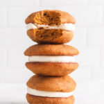 pumpkin whoopie pies with cream cheese filling stacked on top of each other