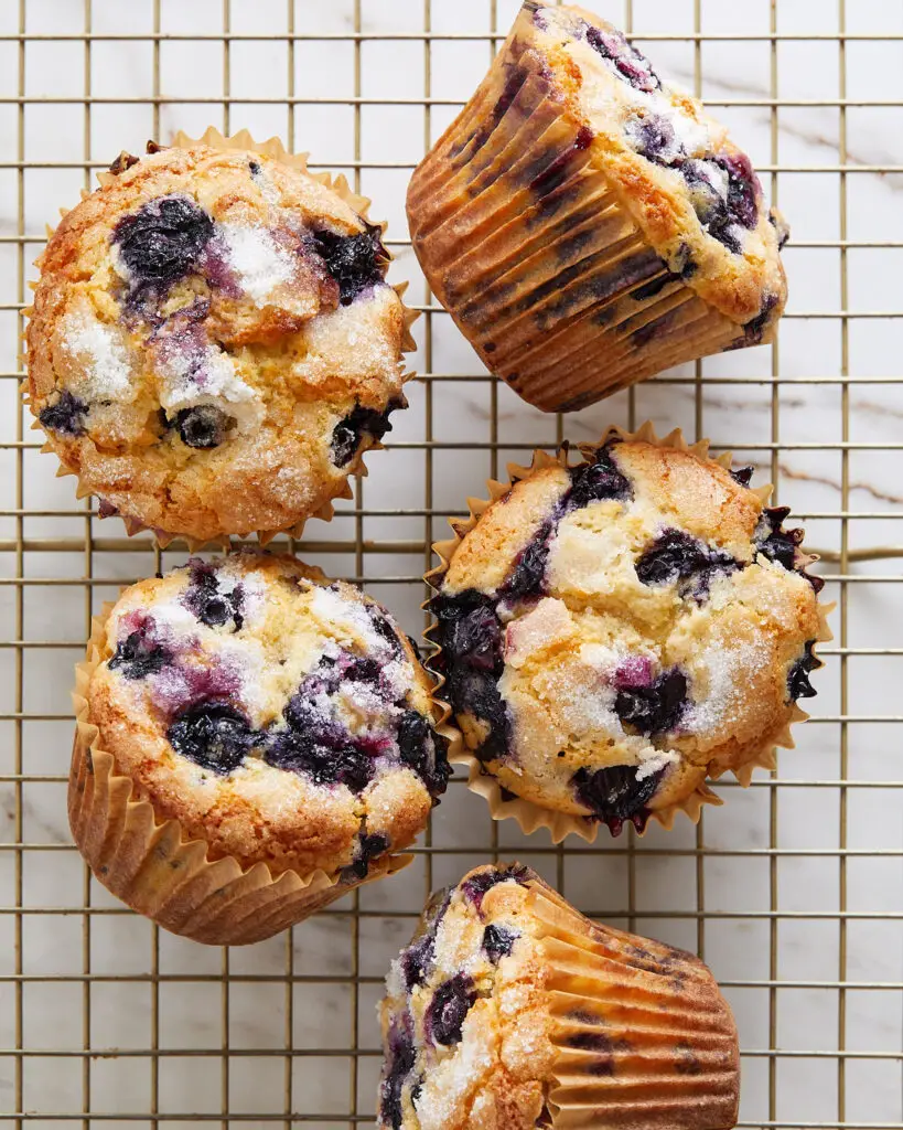 five bakery style blueberry muffins on a cooling rack
