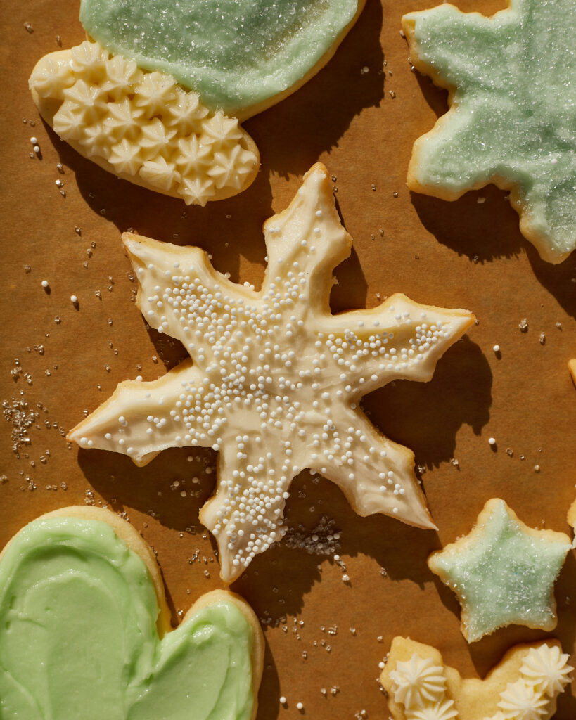 a snowflake sugar cutout cookie cookie, frosted with white buttercream and white sprinkles