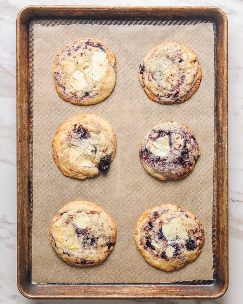 six blueberry white chocolate cookies on a baking sheet