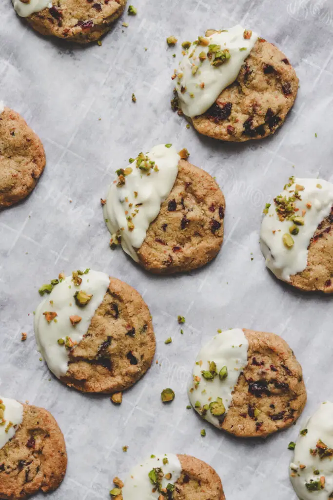 pistachio cranberry shortbread cookies, dipped in white chocolate, on a baking tray