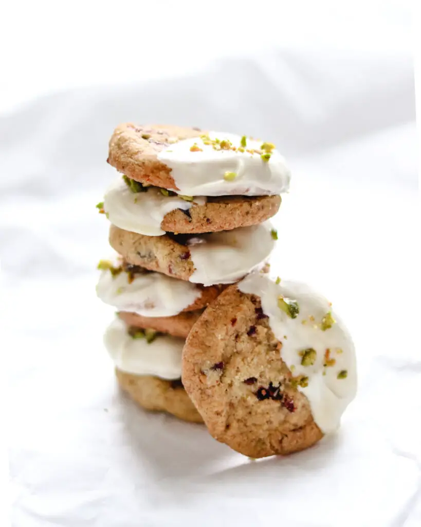 pistachio cranberry shortbread cookies, dipped in white chocolate, stacked on top of each other