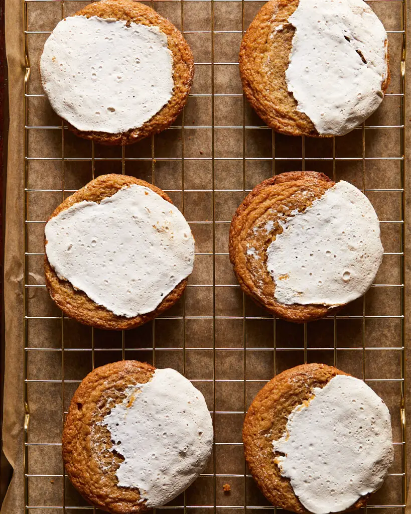 Six chewy peanut butter cookies covered in toasted marshmallow fluff topping, sitting on a cooling rack