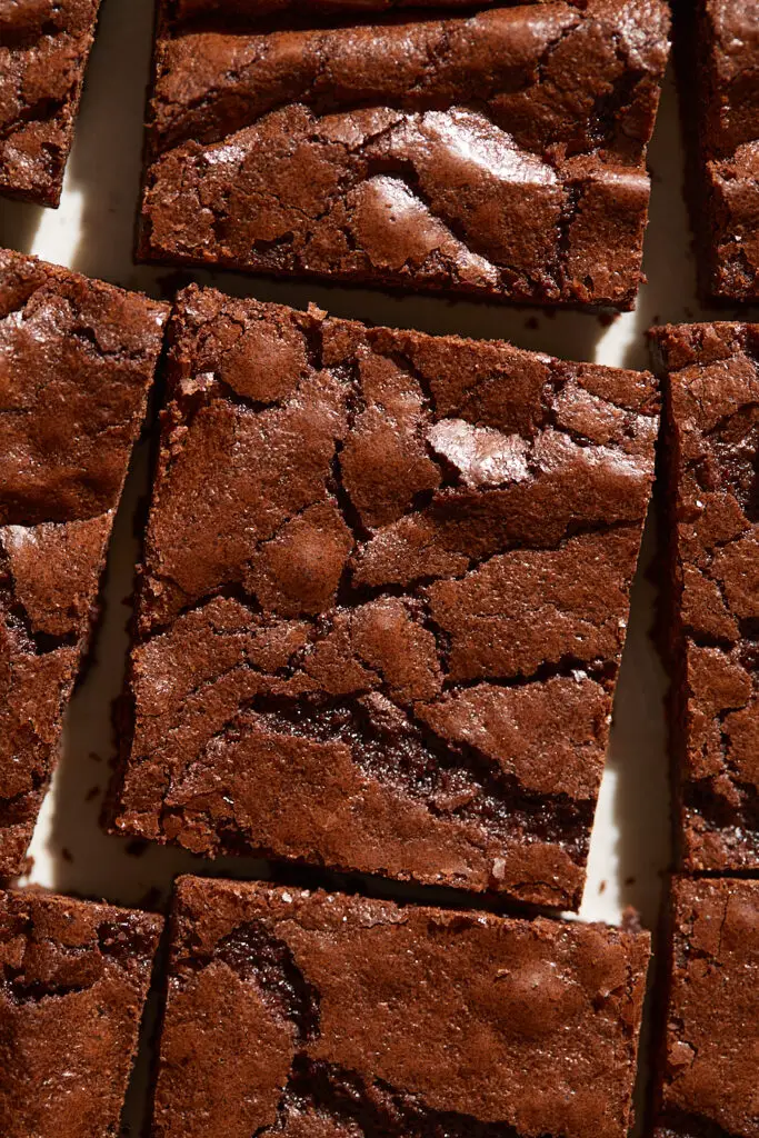 a thin chewy brownie with a shiny, crackly top surrounded by other brownies