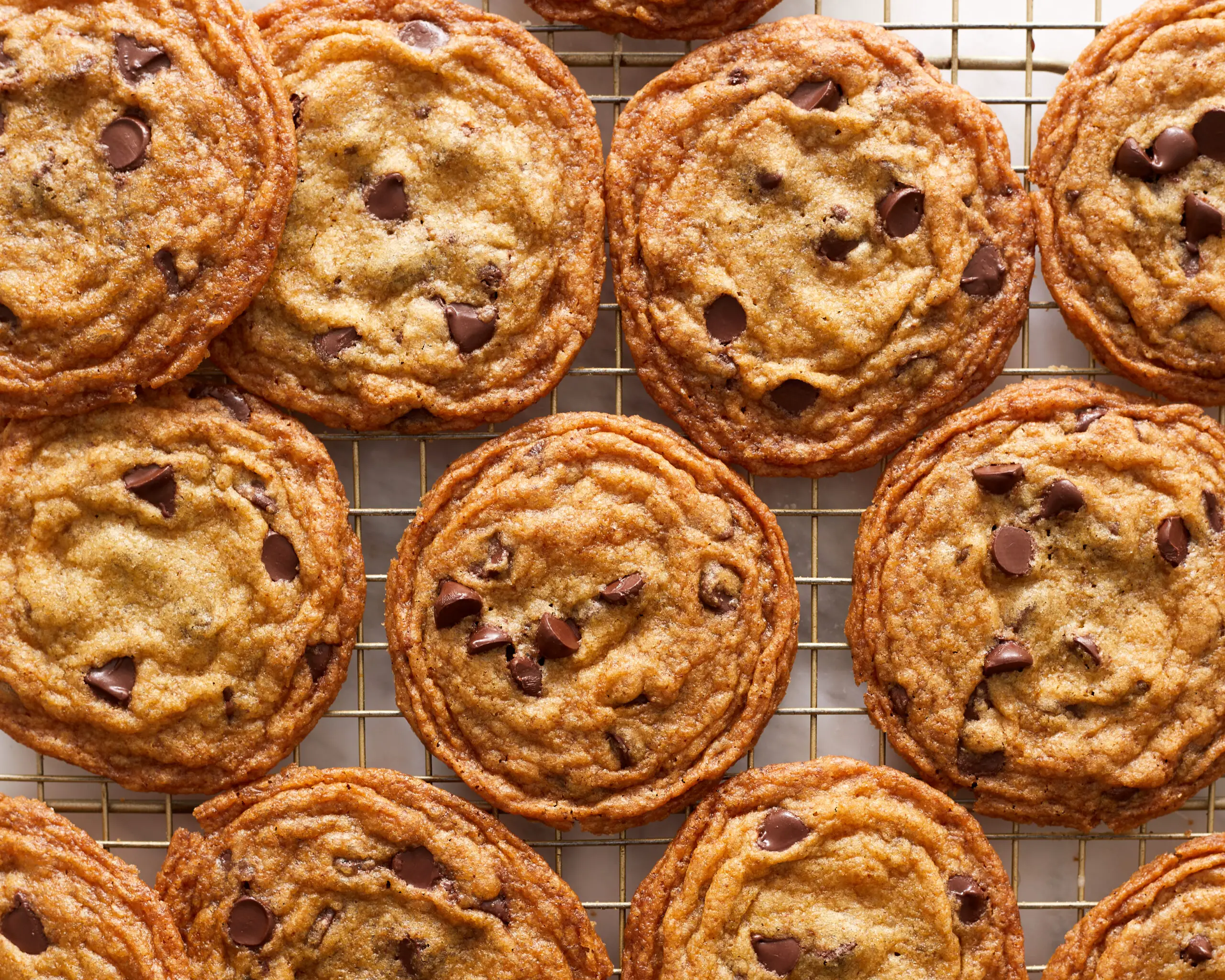several crispy brown butter chocolate chip cookies side by side on a cooling rack