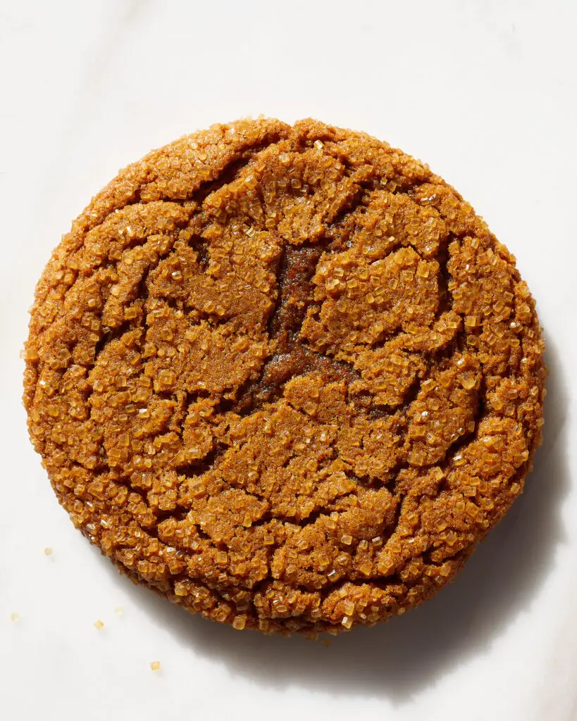 a chewy ginger molasses cookies with big crinkles on a white marble surface