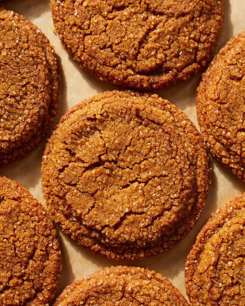 several chewy ginger molasses cookies with sparkly sugar coating on a baking sheet 