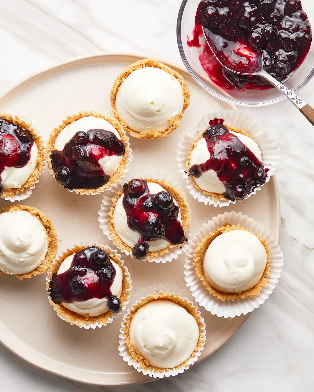 Mini no-bake cheesecakes topped with a blueberry compote on a serving plate