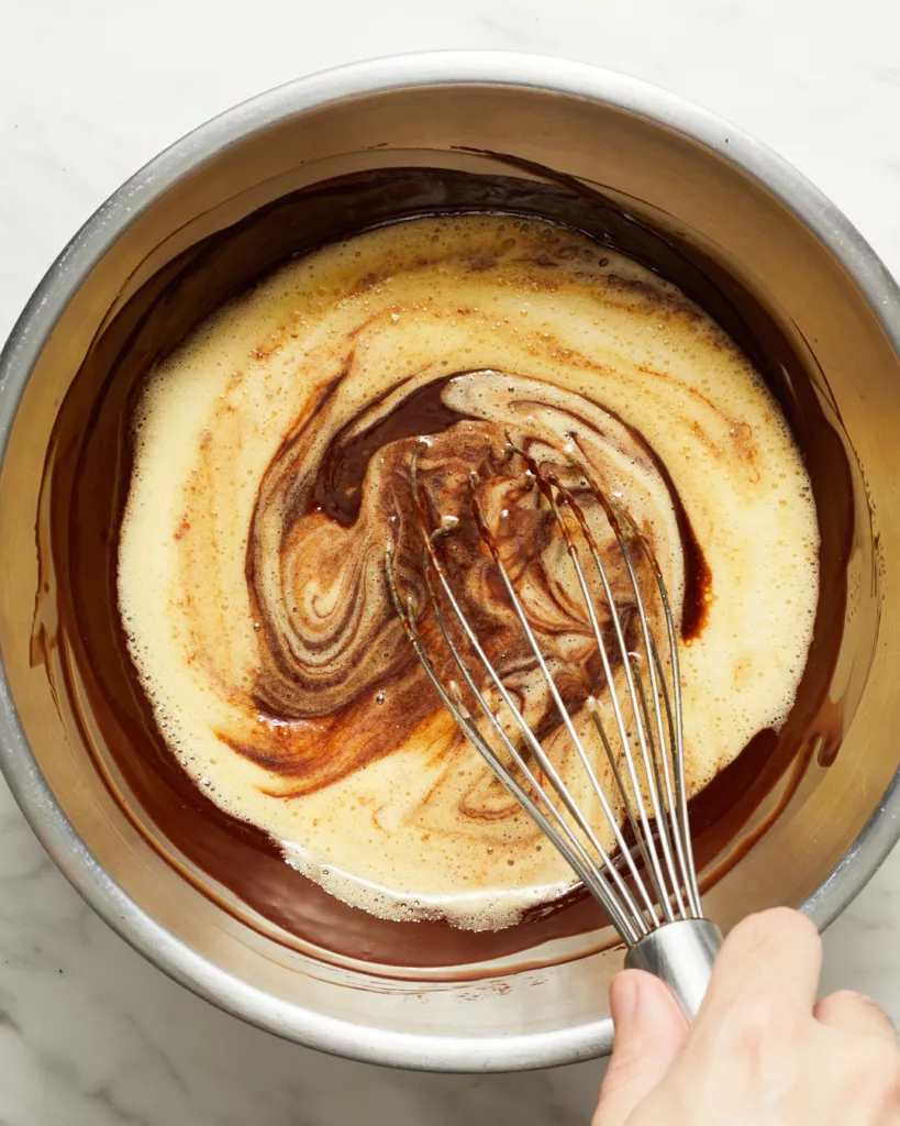 mixing whipped eggs and sugar into chocolate and butter for molten chocolate lava cake batter