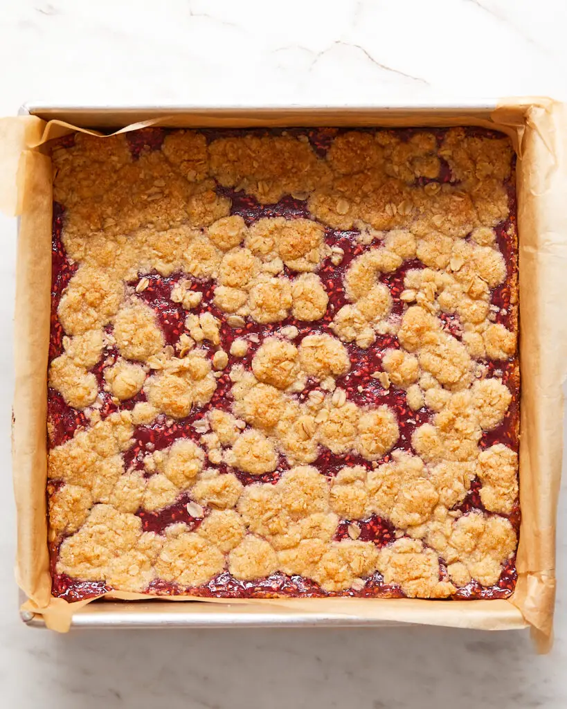 A 9x9 inch tin of oat raspberry bars lined with parchment paper