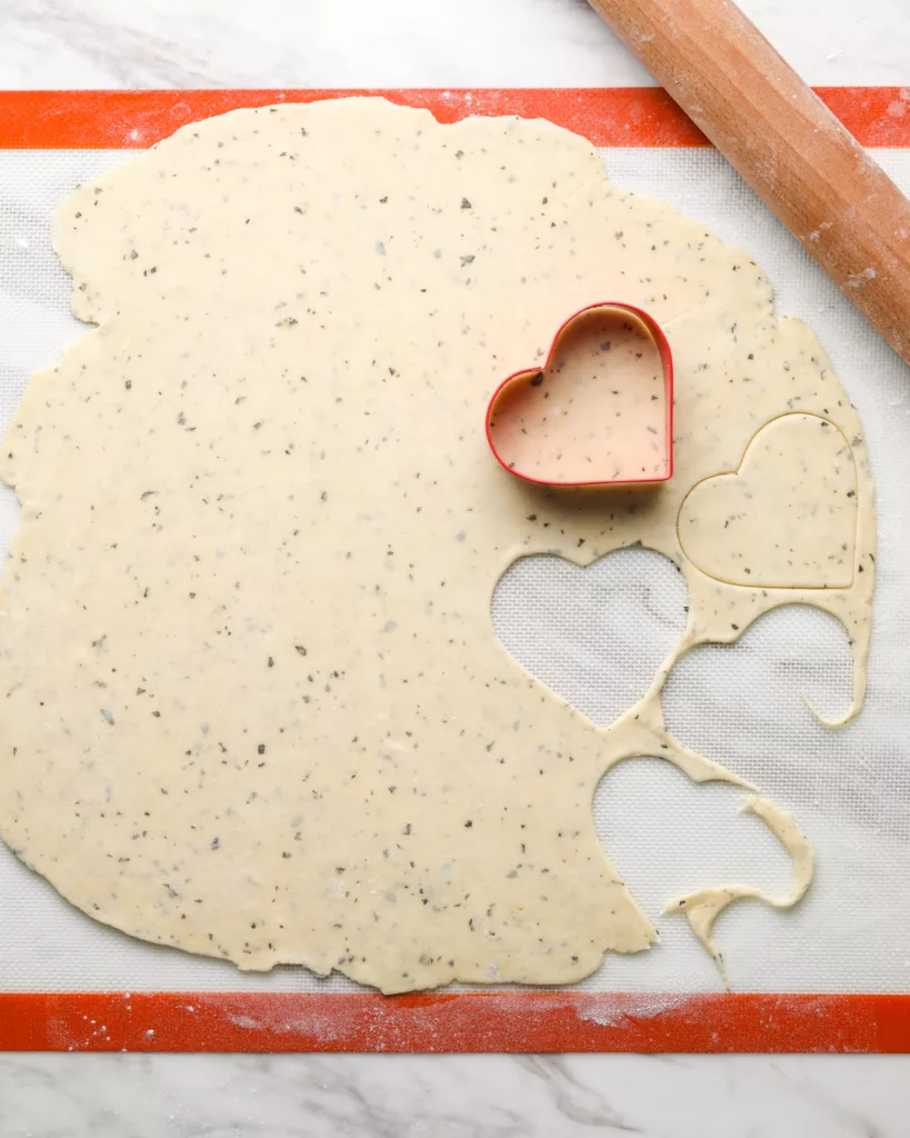 a cookie cutter cuts out heart shapes out of pie crust