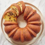 a sour cream chocolate chip bundt cake on a serving plate cut into slices