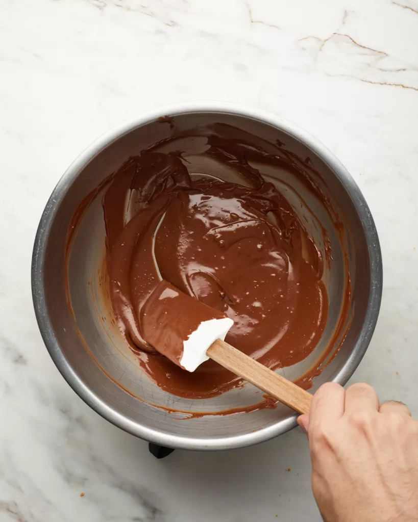 a white rubber spatula mixes melted chocolate and butterscotch chips together