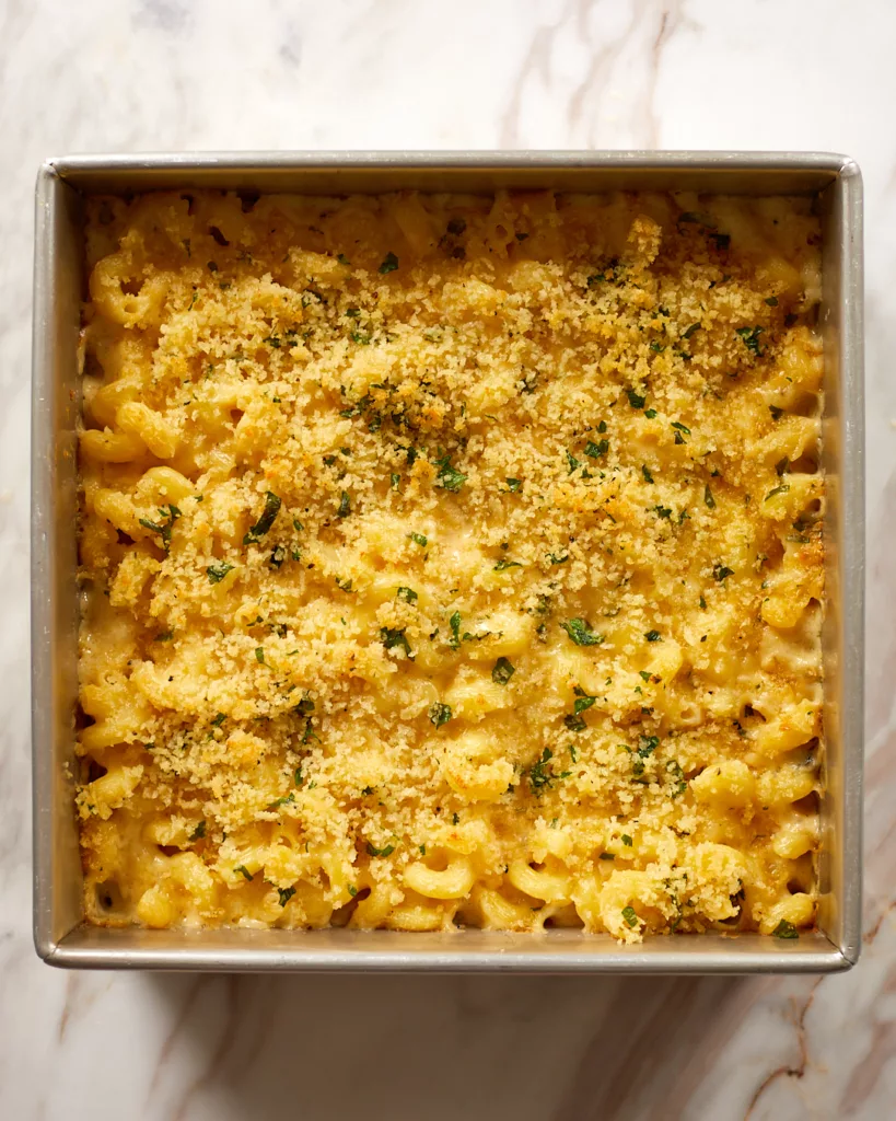 a 9x9 inch tin full of 4 cheese macaroni and cheese topped with buttery toasted breadcrumbs