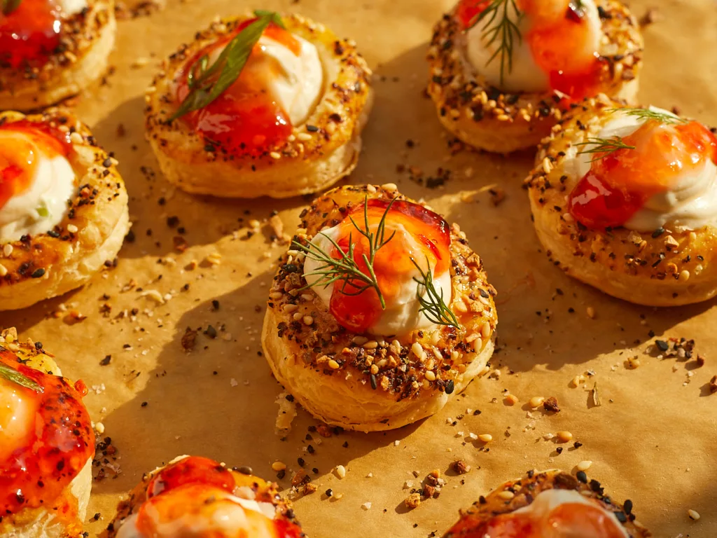 everything bagel puff appetizers with cream cheese filling and pepper jelly sitting on a baking sheet