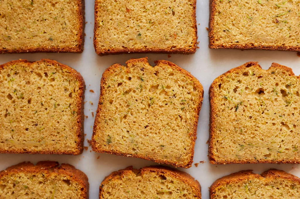 olive oil zucchini bread slices lined up on a marble surface