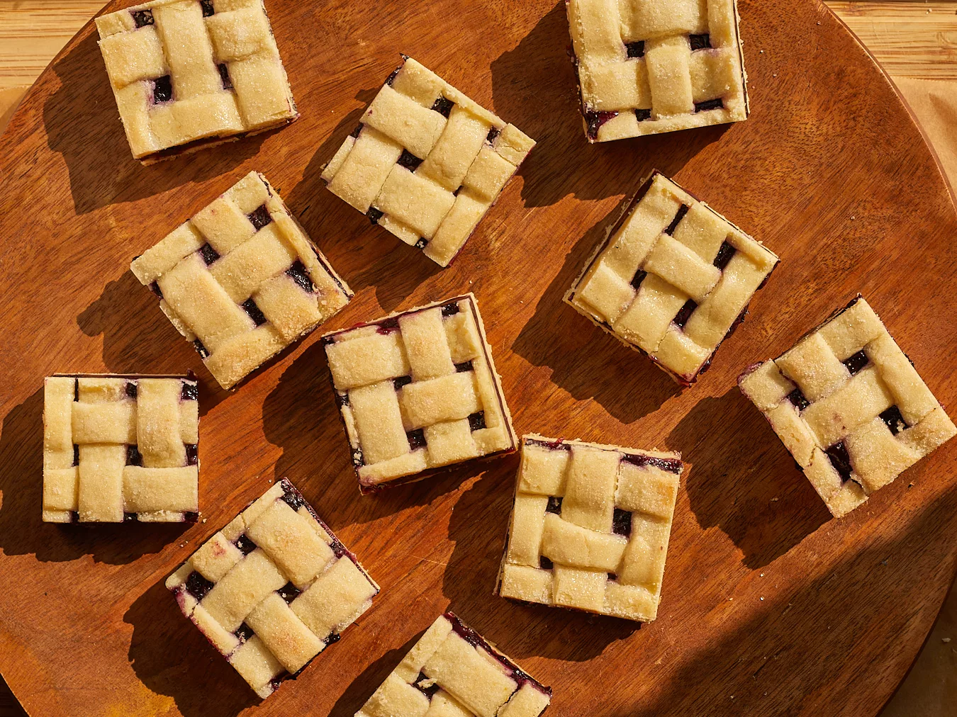 blueberry pie bars with lattice top sliced into squares on a wood background