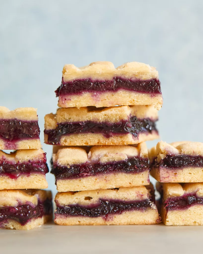 blueberry pie bars in three stacks in front of a blue background