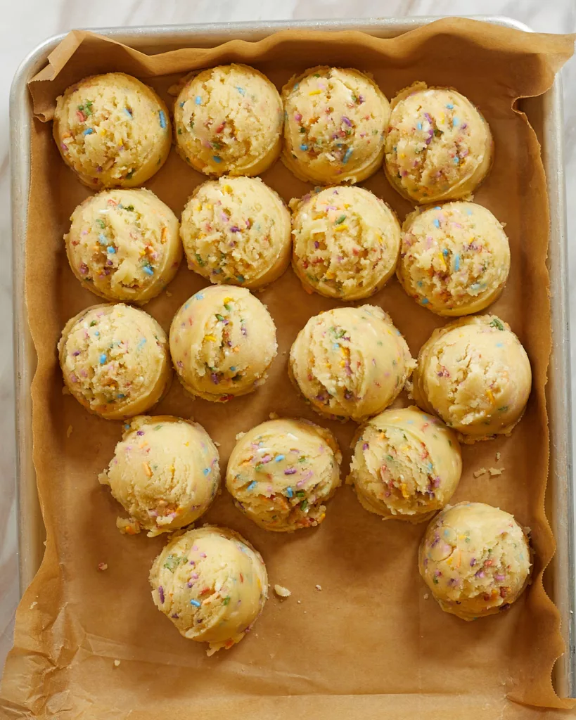 dough balls of confetti cookie dough on a parchment lined tray