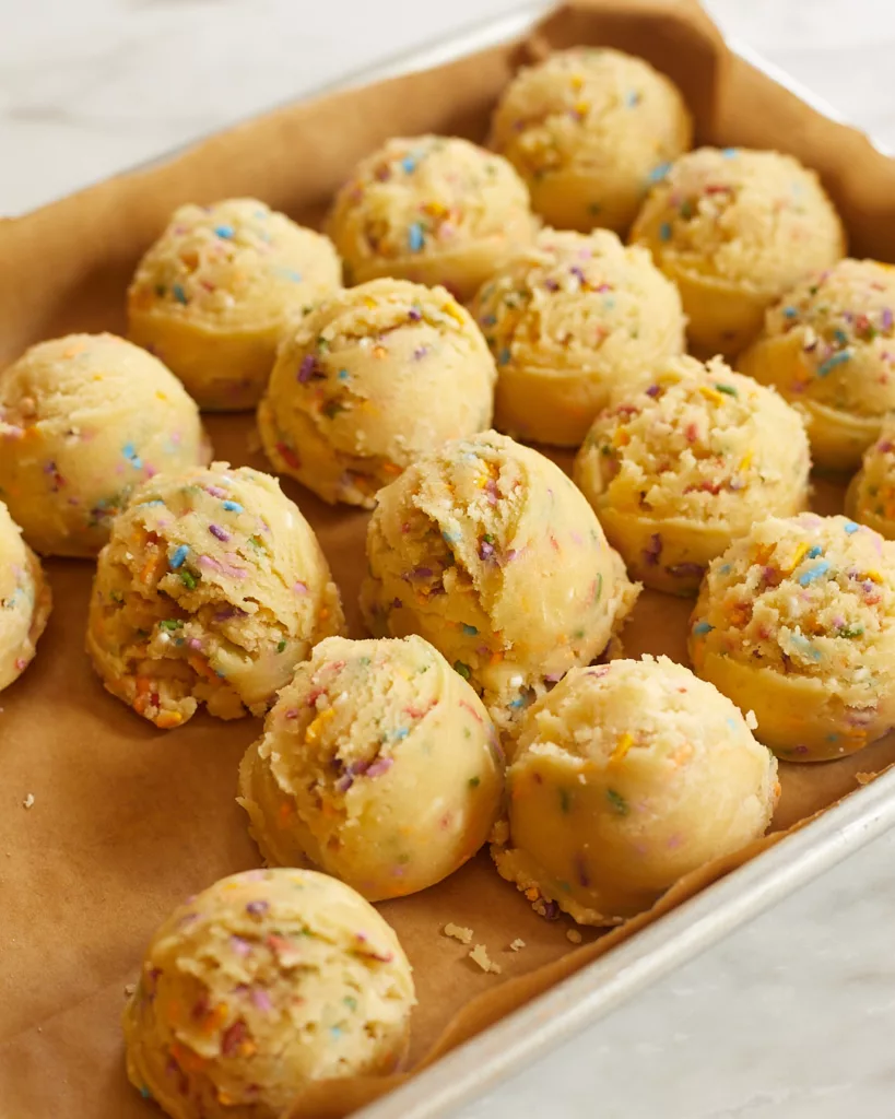 dough balls of confetti cookie dough on a parchment lined tray
