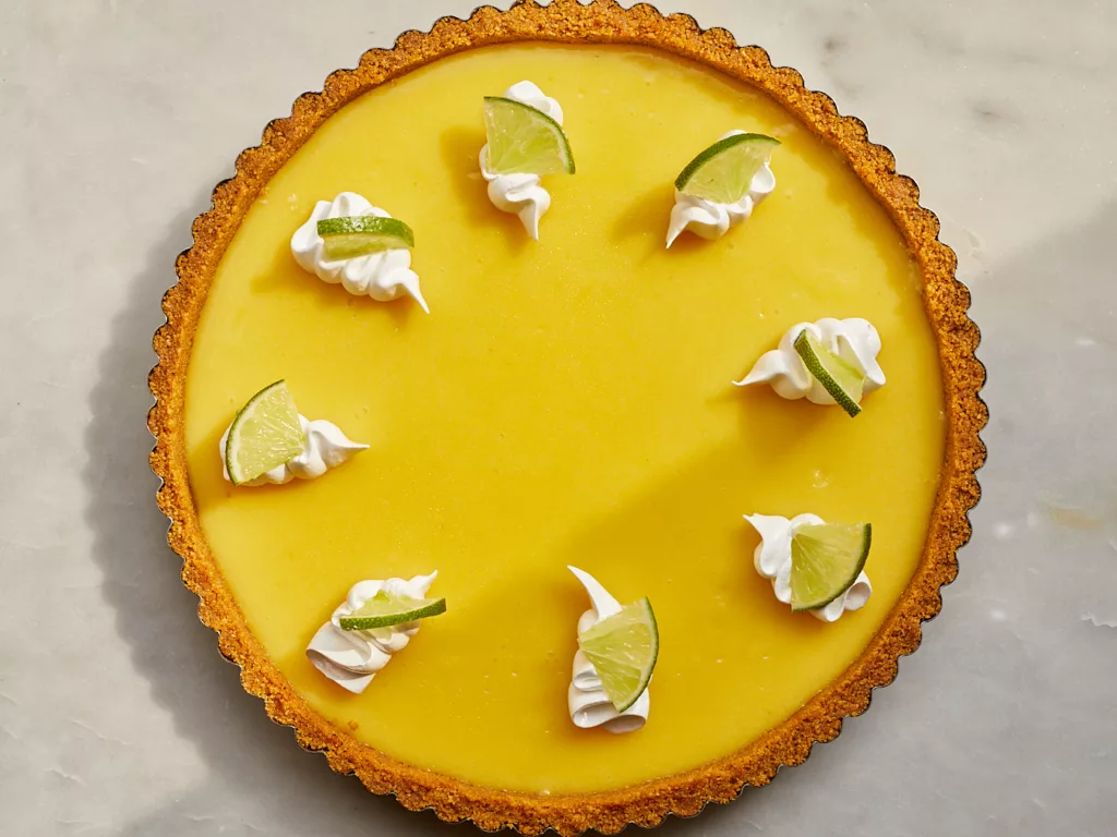 a no bake key lime tart with swirls of meringue topping and lime slices