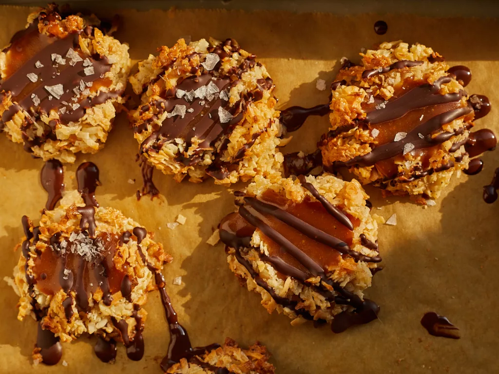 chocolate caramel macaroons sit on a parchment lined tray