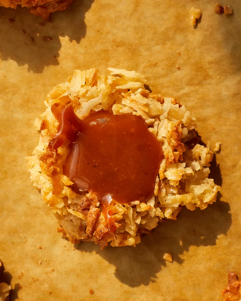 a macaroon with salted caramel filling sit on a parchment lined half sheet tray