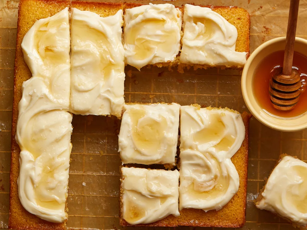 cornbread snacking cake cut into slices on a wire rack with a pot of honey to the side