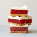 watermelon strawberry jello bars with layers of pretzel shortbread and whipped cream stacked on top of each other