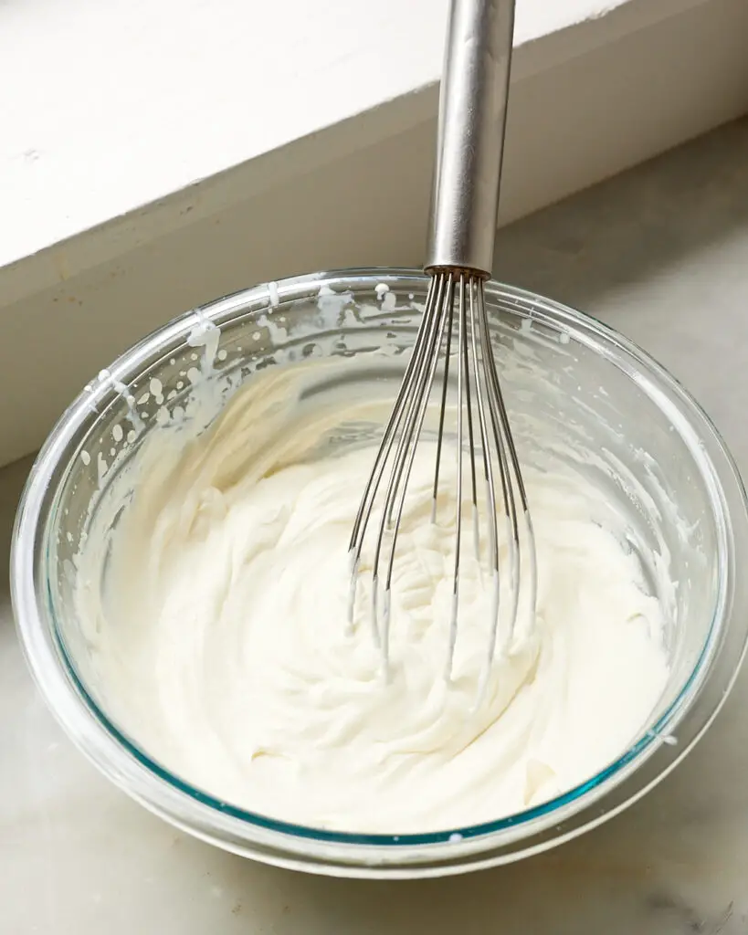 A bowl of crème fraîche whipped cream with a whisk sticking out