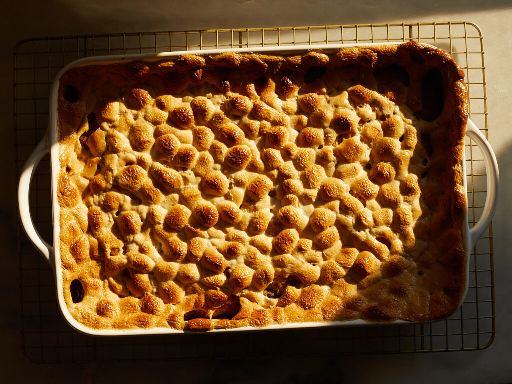 A tray of yellow cake picnic cake with toasted marshmallows on top