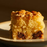 A slice of picnic cake with chocolate chips and marshmallows sits on a dessert plate