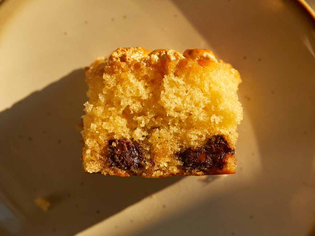 A slice chocolate chip-marshmallow picnic cake sits on a marble surface