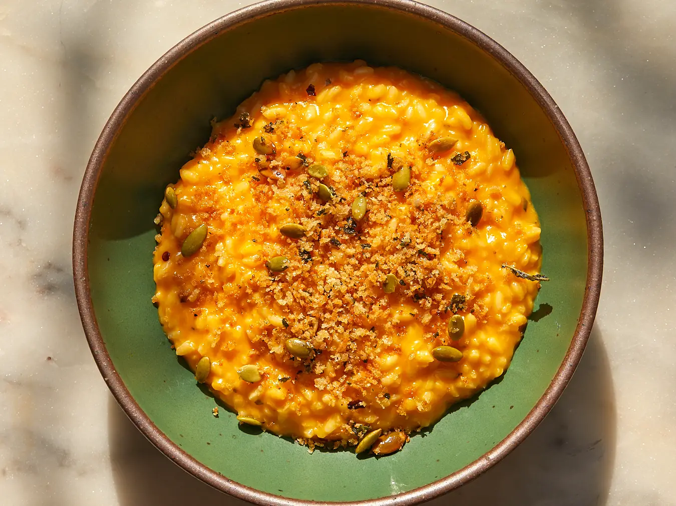 cheesy butternut squash risotto with breadcrumb topping in a shallow green bowl