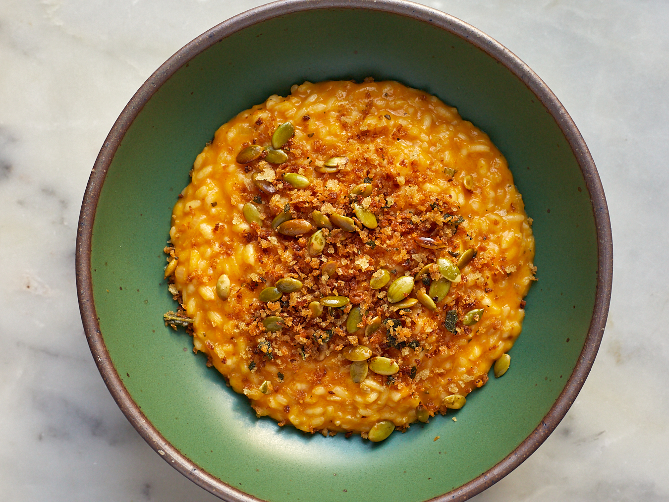 cheesy butternut squash risotto with breadcrumb topping in a shallow green bowl