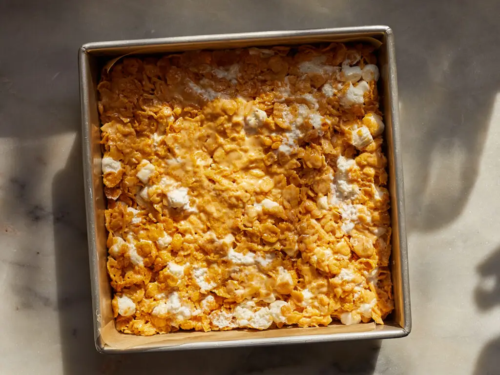 butterscotch corn flake treats made with marshmallows and browned butter pressed into a square tin