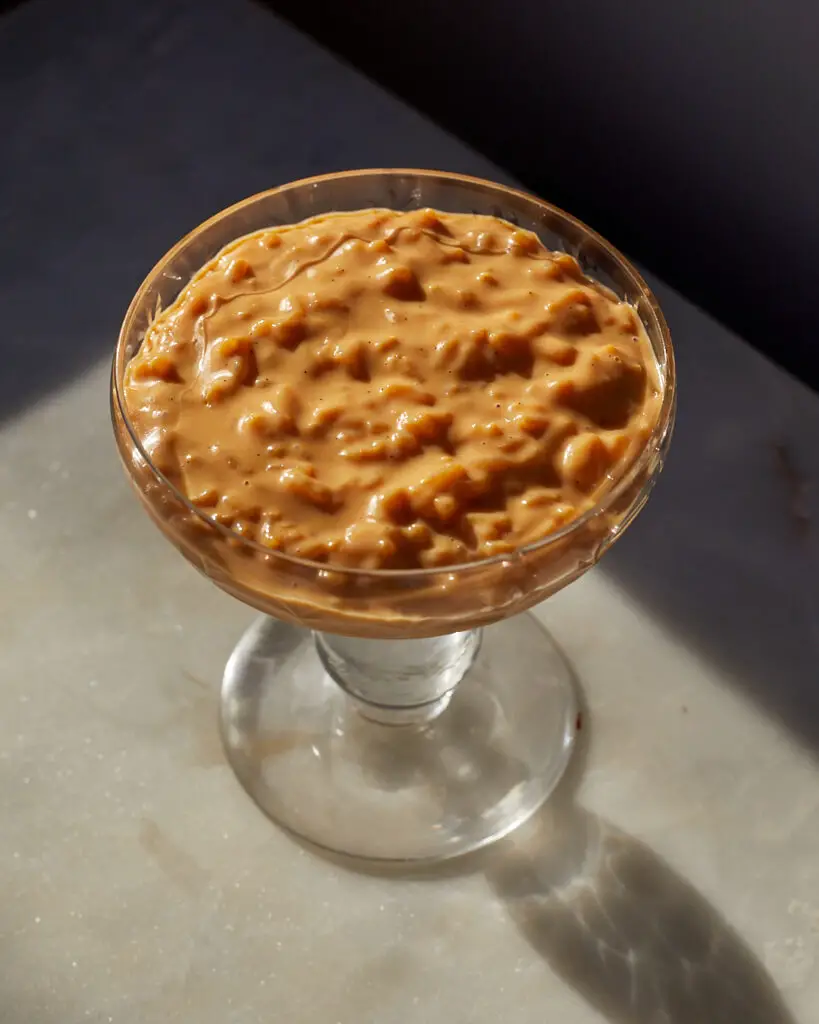 caramel rice pudding in a crystal glass on a marble surface