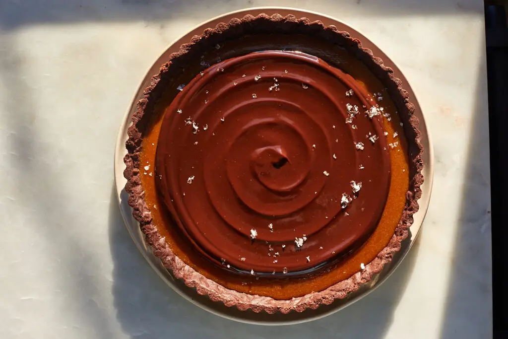 a swirl of coffee chocolate ganache tops salted caramel filling in a coffee caramel chocolate tart