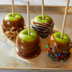 caramel apples decorated with chocolate peanuts and m&ms