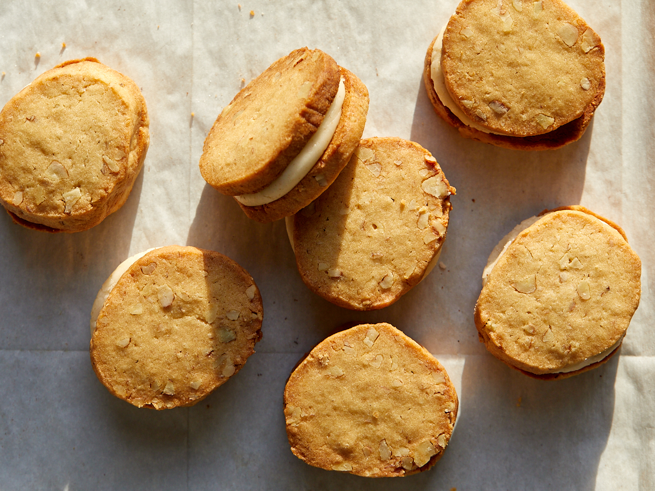 caramel cream pecan sandies sandwiches with browned butter filling on a sheet tray