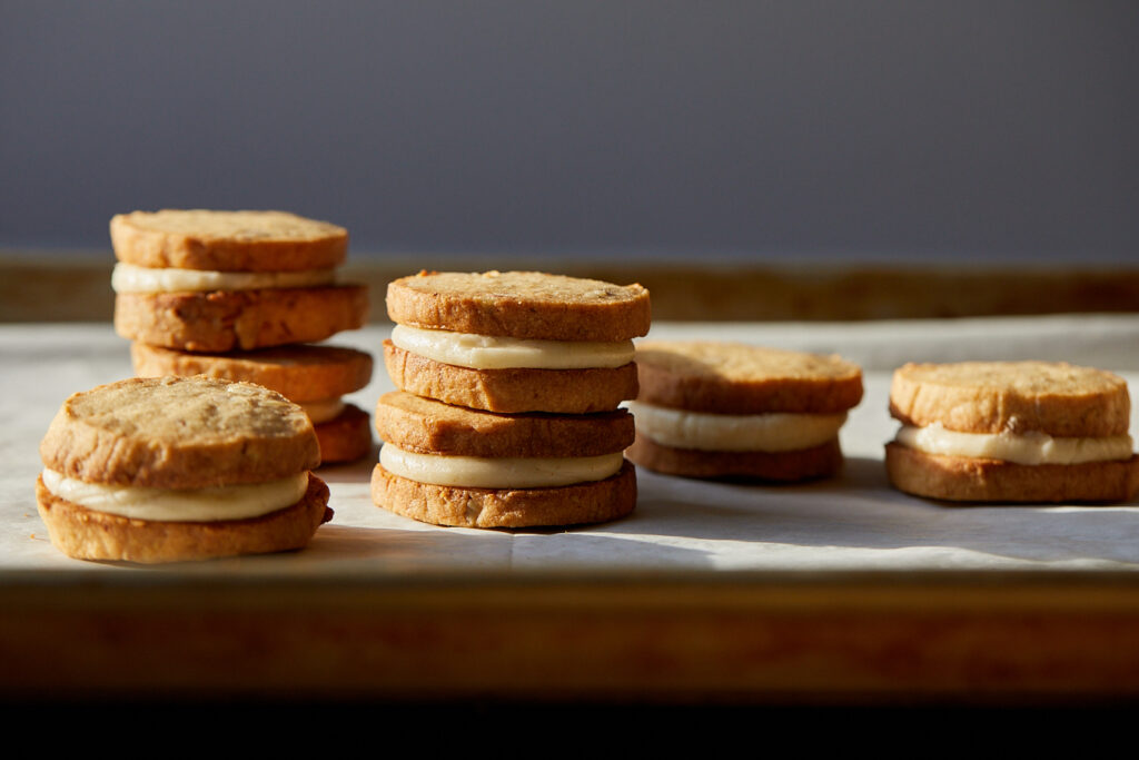 caramel creams pecan sandies with browned butter filling are stacked in little columns on a sheet tray