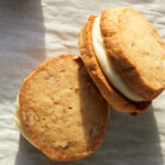 caramel cream pecan sandies sandwiches with browned butter filling on a sheet tray