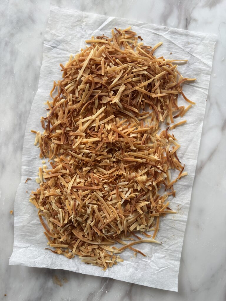 piles of toasted coconut on a sheet of parchment paper