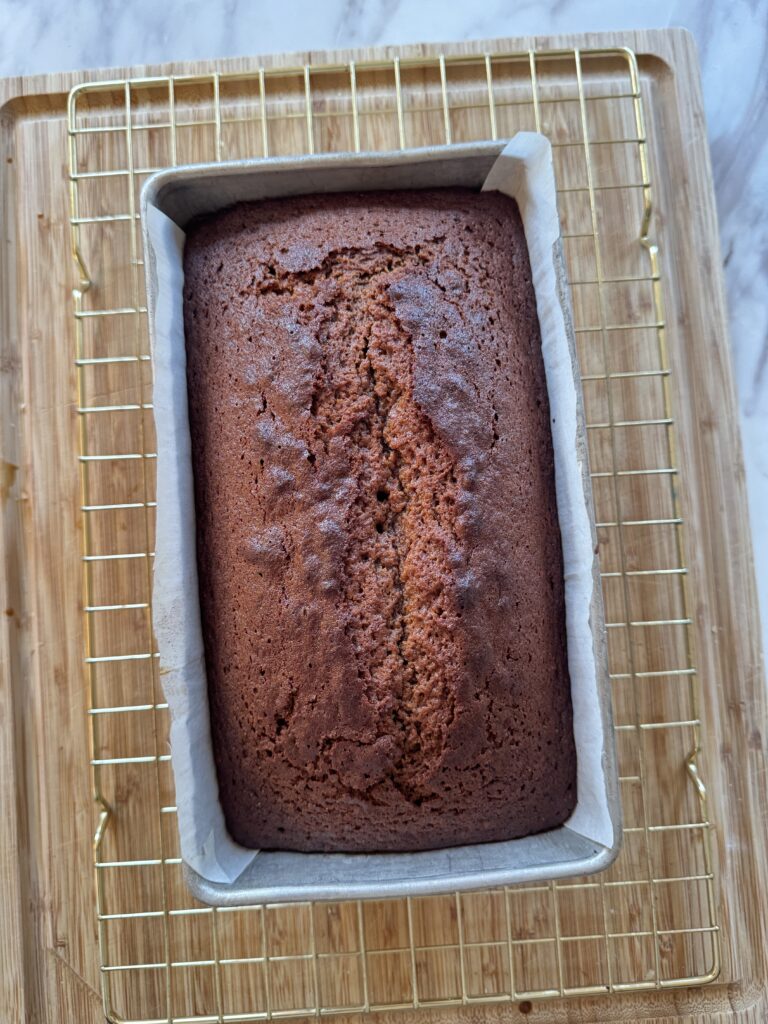 A tin of gingerbread loaf cake on a cooling rack