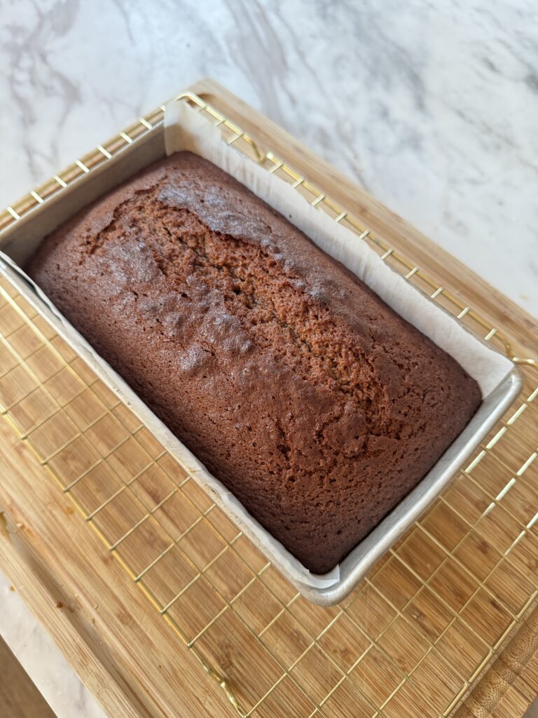 A tin of gingerbread loaf cake on a cooling rack