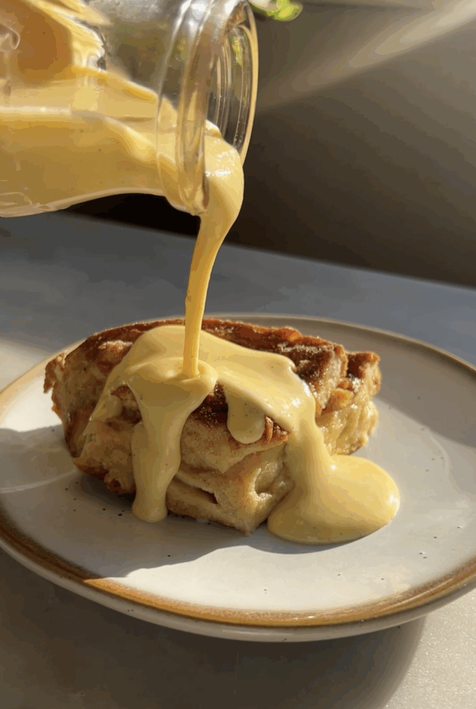 A slice of eggnog french toast bake with eggnog creme anglaise poured on top