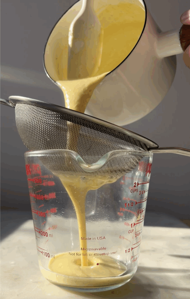 creme anglaise being strained through a sieve