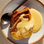 A slice of eggnog french toast bake with eggnog creme anglaise poured on top