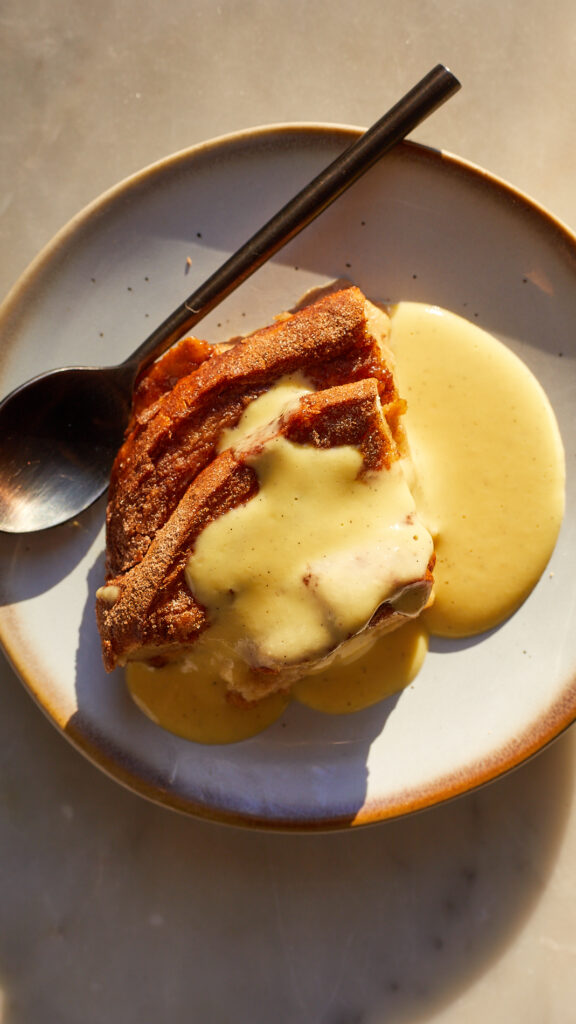 A slice of eggnog french toast bake with eggnog creme anglaise poured on top