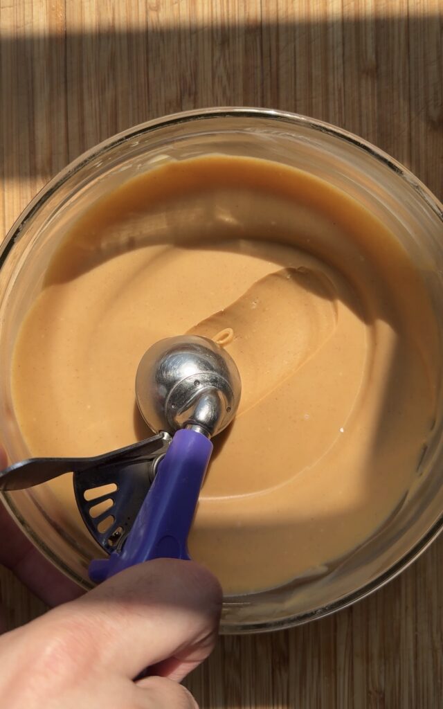 A purple portion scoop scooping up peanut butter filling for buckeye cookies